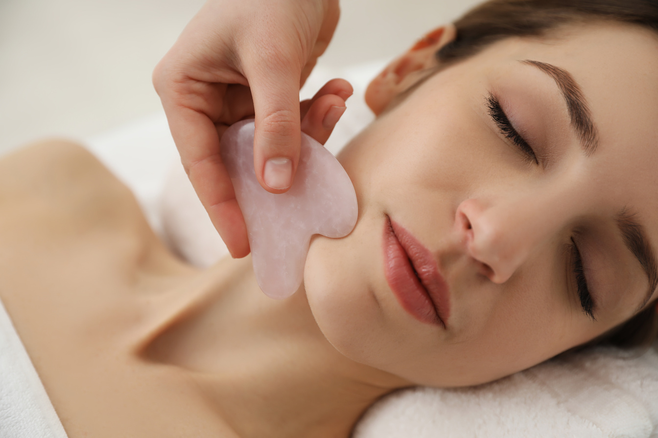 Young Woman Receiving Facial Massage with Gua Sha Tool in Beauty